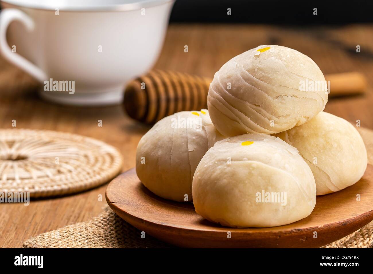 Nahaufnahme von hausgemachtem chinesischem Gebäck oder Mondkuchen gefüllt mit süßer Mungbohnenpaste und gesalzenem Eigelb auf Holzplatte auf Sacktuch mit Whi legen Stockfoto