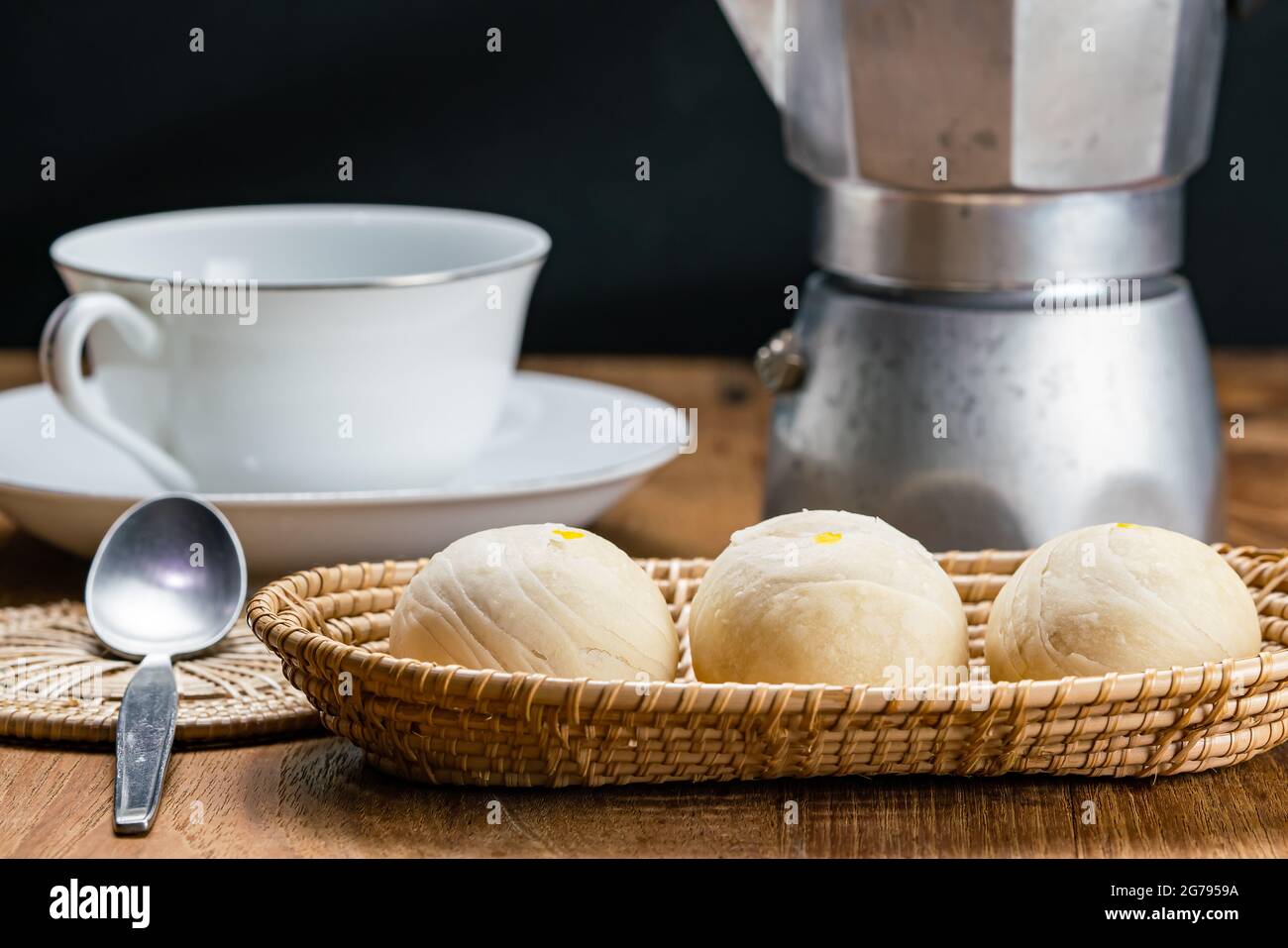 Blick auf hausgemachtes chinesisches Gebäck oder Mondkuchen gefüllt mit süßer Mungbohnenpaste und gesalzenem Eigelb in Bambusablage mit weißer Keramikschale, Mo Stockfoto
