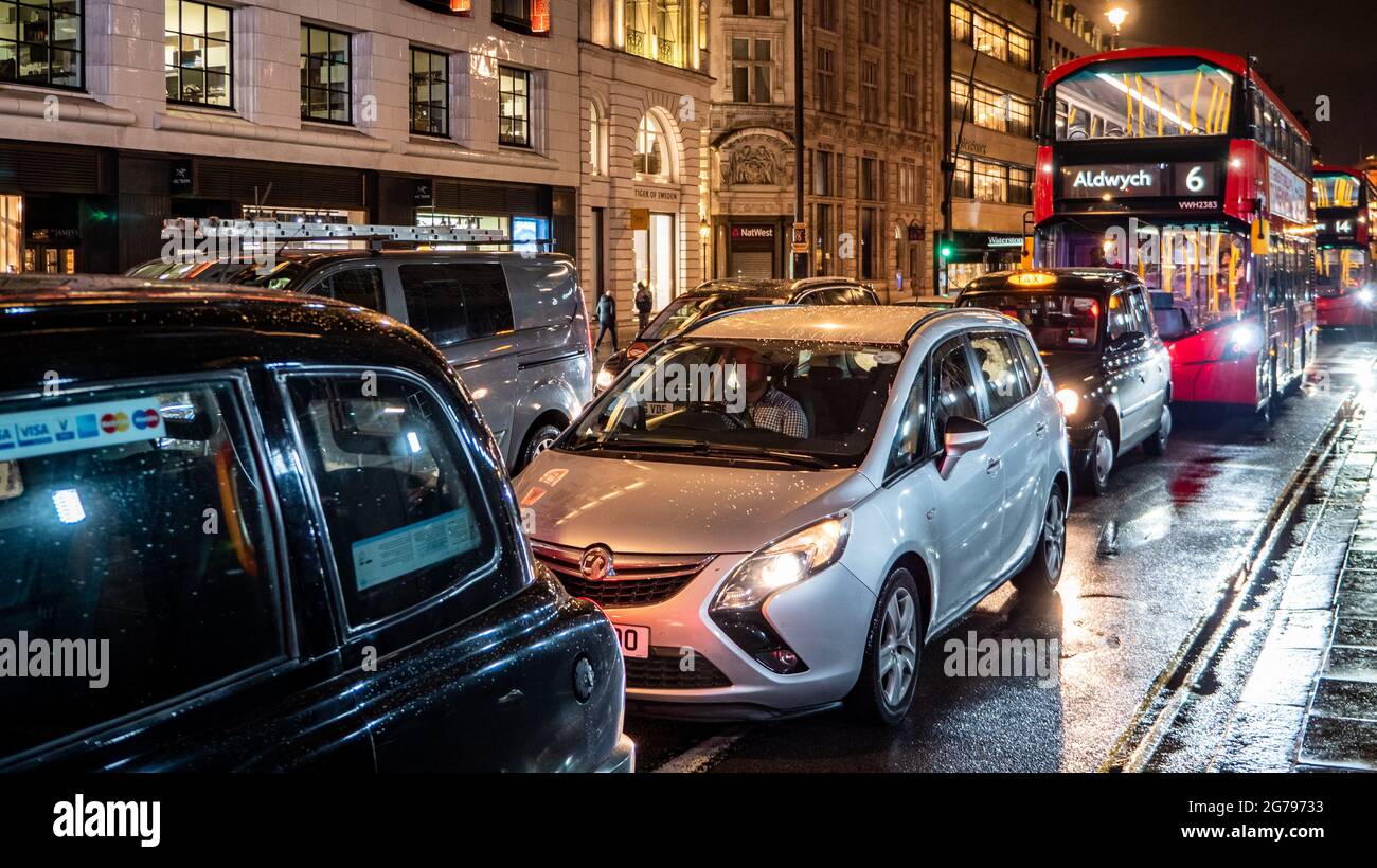 Verkehr In London. Ein Stau in der späten Nacht auf den nassen Straßen von Londons Strand mit bekannten roten Bussen und schwarzen Taxis im Verkehr. Stockfoto