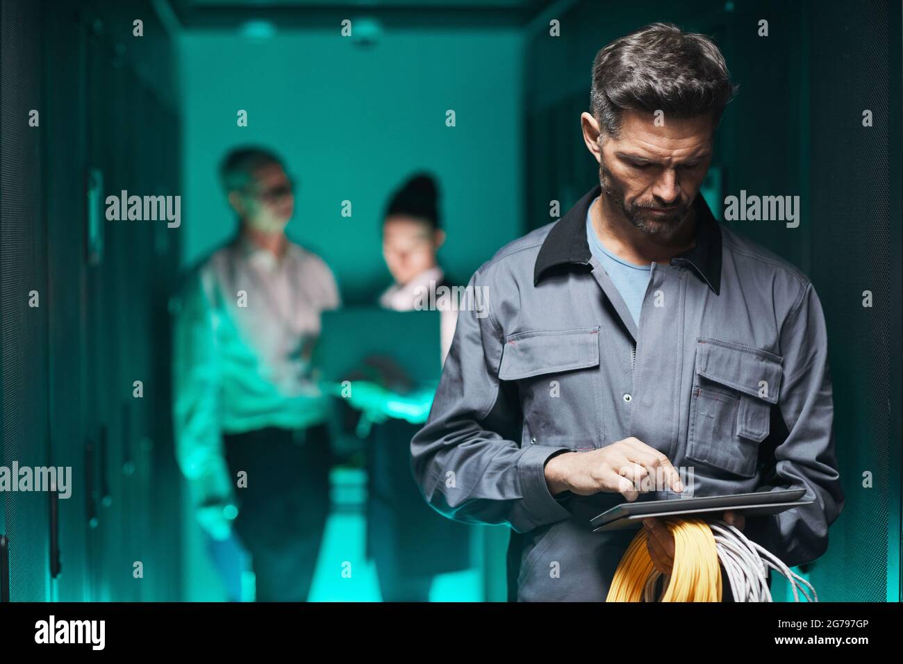 Porträt eines reifen Netzwerktechnikers, der während der Wartungsarbeiten im Rechenzentrum ein digitales Tablet im Serverraum verwendet, und des Kopierplatzes Stockfoto