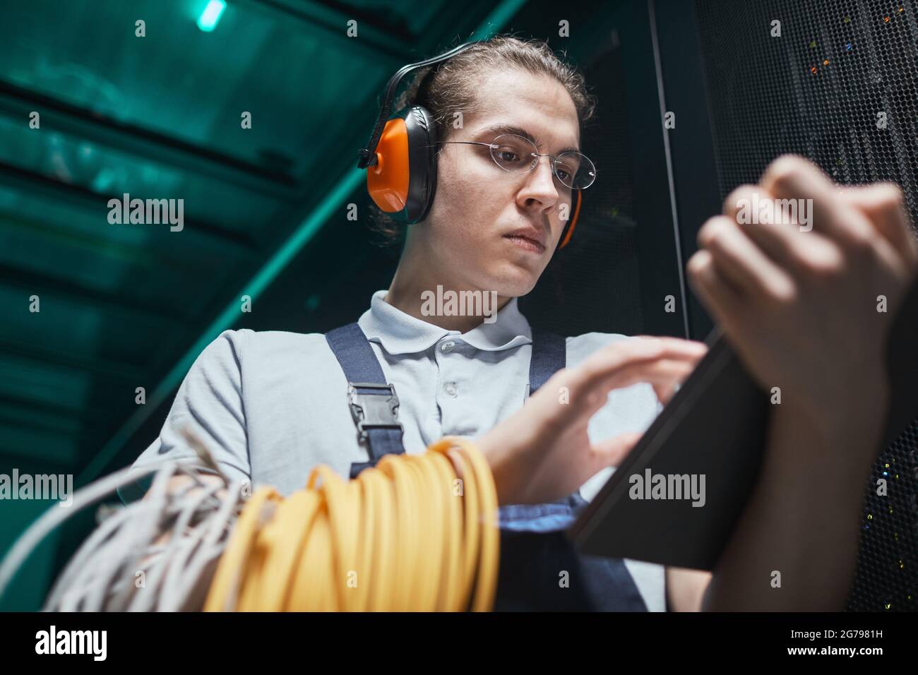 Porträt eines jungen Netzwerktechnikers, der während der Wartungsarbeiten im Rechenzentrum im Serverraum ein digitales Tablet verwendet, Kopierfläche Stockfoto