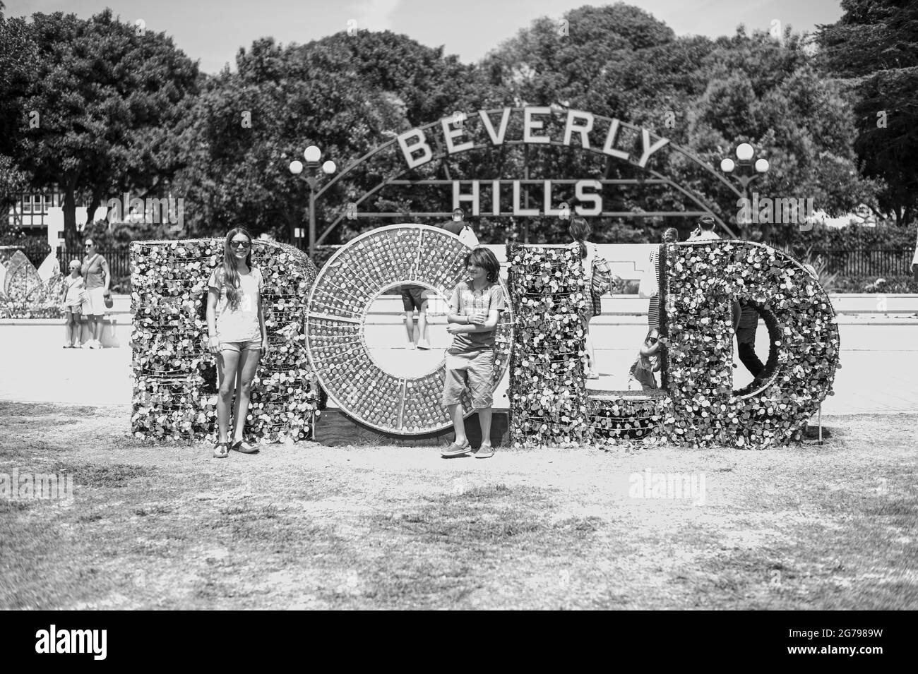 Schwarz-Weiß-Aufnahme eines kaukasischen Mädchens, 15-20 Jahre und kaukasischer Junge, 10-15 Jahre vor Beverly Hills Schild in Beverly Hills, Los Angeles, Kalifornien, USA Stockfoto