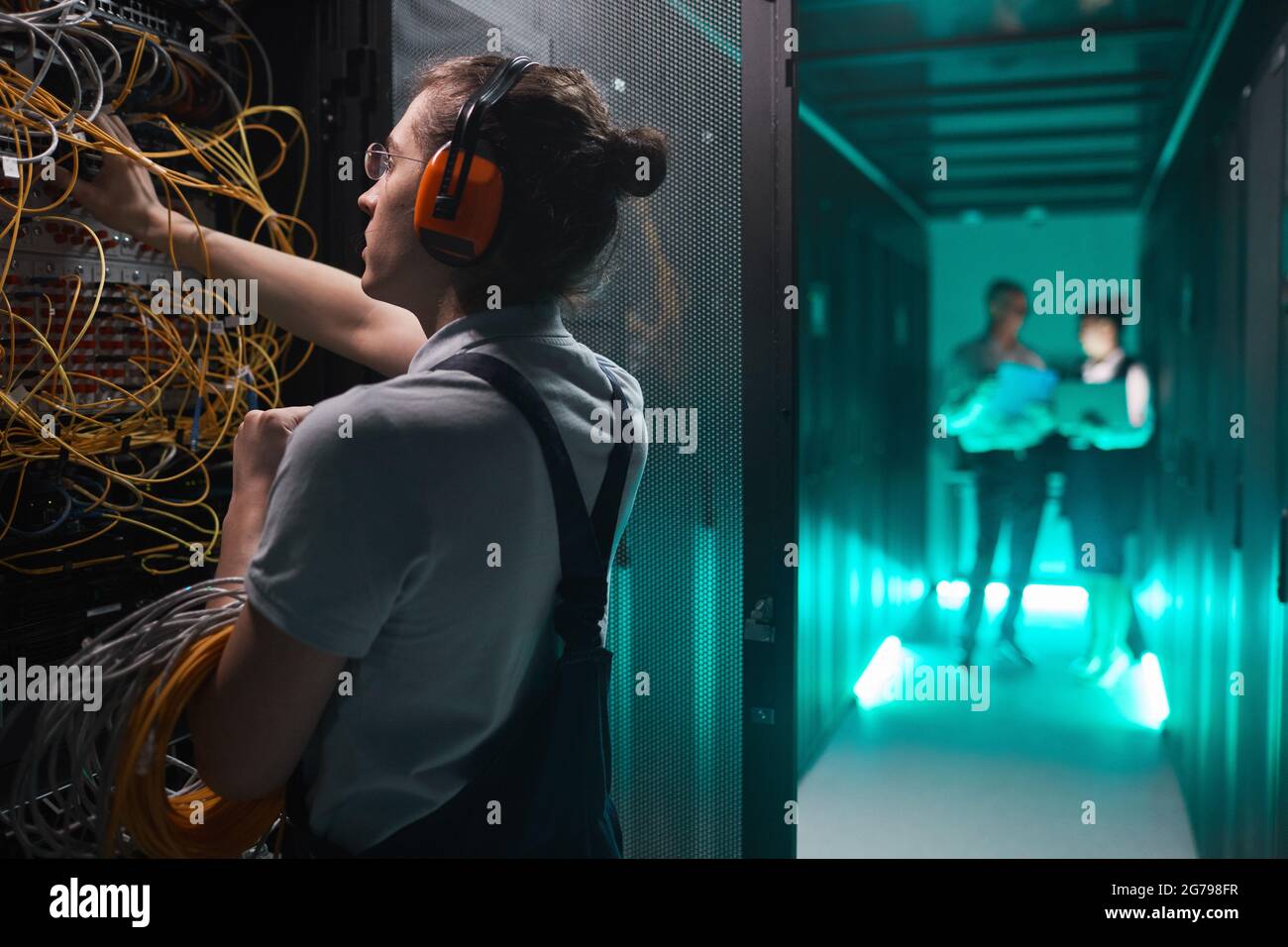 Seitenansicht Porträt eines jungen Netzwerktechnikers im Serverraum, der Wartungsarbeiten im Rechenzentrum und Platz für Kopien macht Stockfoto