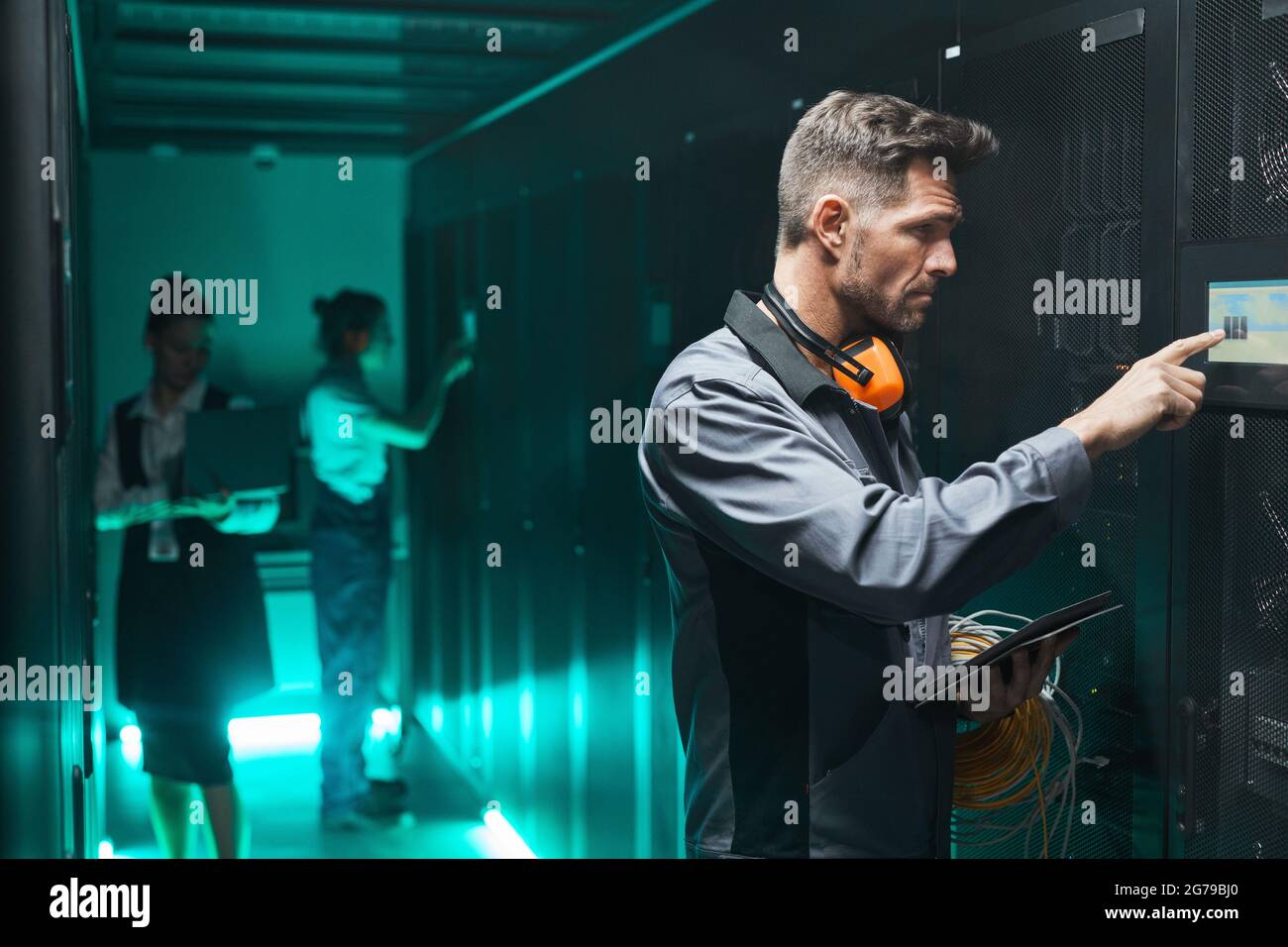 Seitenansicht Porträt eines männlichen Netzwerktechnikers, der während des Betriebs des Servers im Rechenzentrum das Bedienfeld verwendet, Speicherplatz kopieren Stockfoto