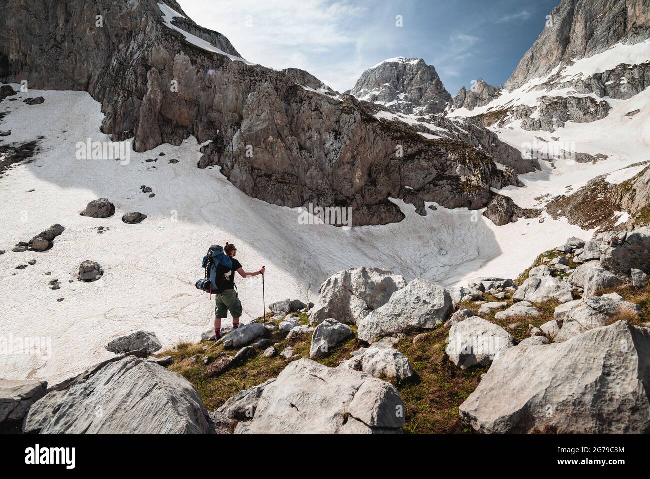 Einzelne Wanderer stehen mitten in der Berglandschaft des Prokletije Nationalparks und blicken über die Schneefelder nach Maja Jezerce, Albanien Stockfoto