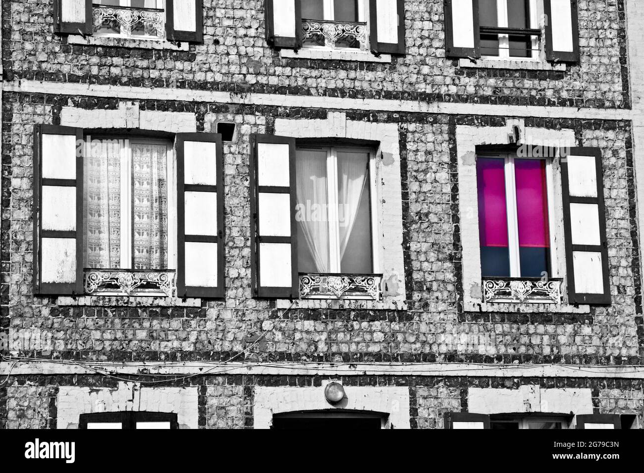 Mystisches rotes Fenster in schwarz-weißer Hauswand im Alptraum Stockfoto