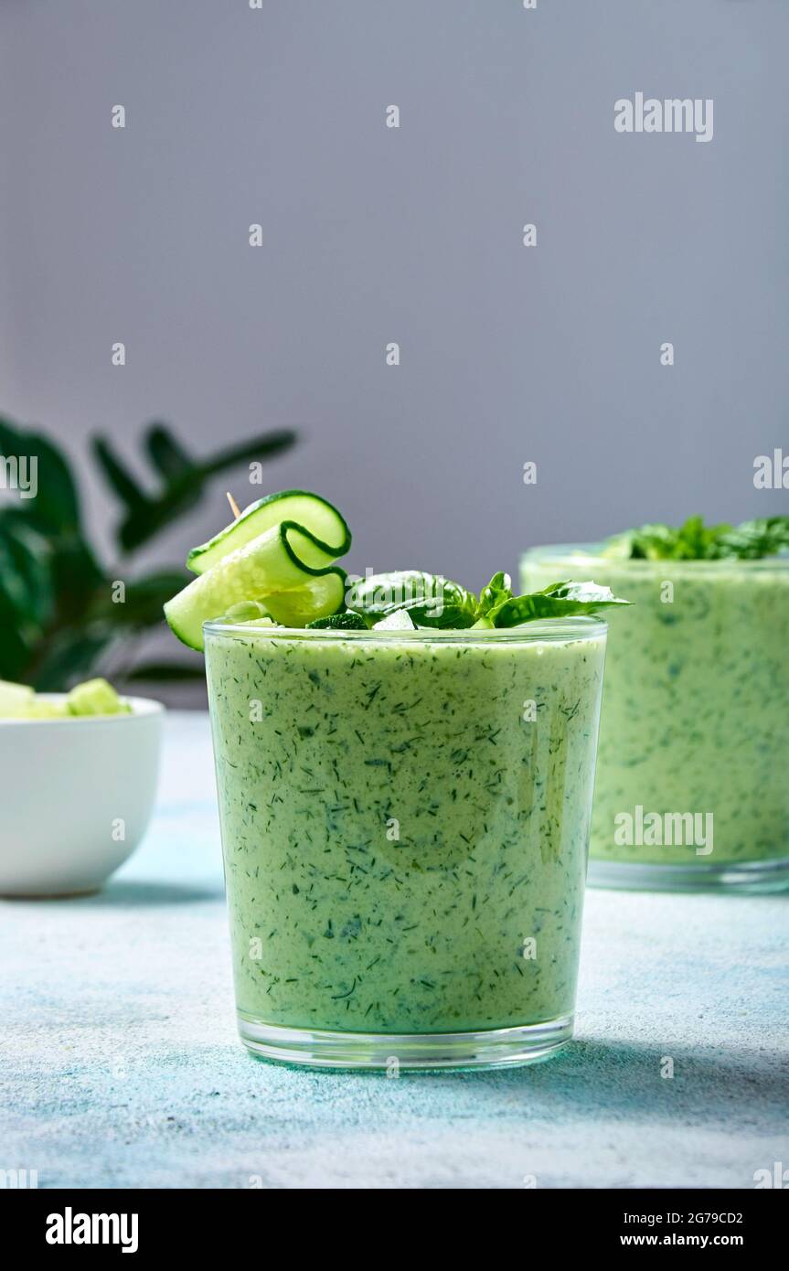 Gurke Gazpacho - kalte Sommersuppe mit Basilikum in Gläsern auf hellem Hintergrund. Stockfoto