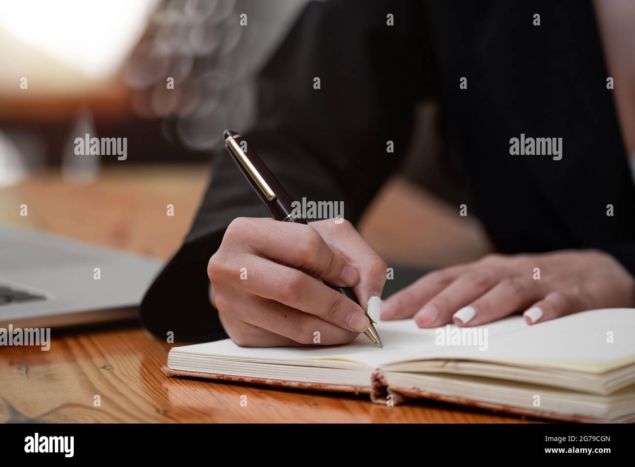Nahaufnahme der Hand einer Frau, die den Stift hält und mit dem Laptop am Tischbüro arbeitet Stockfoto