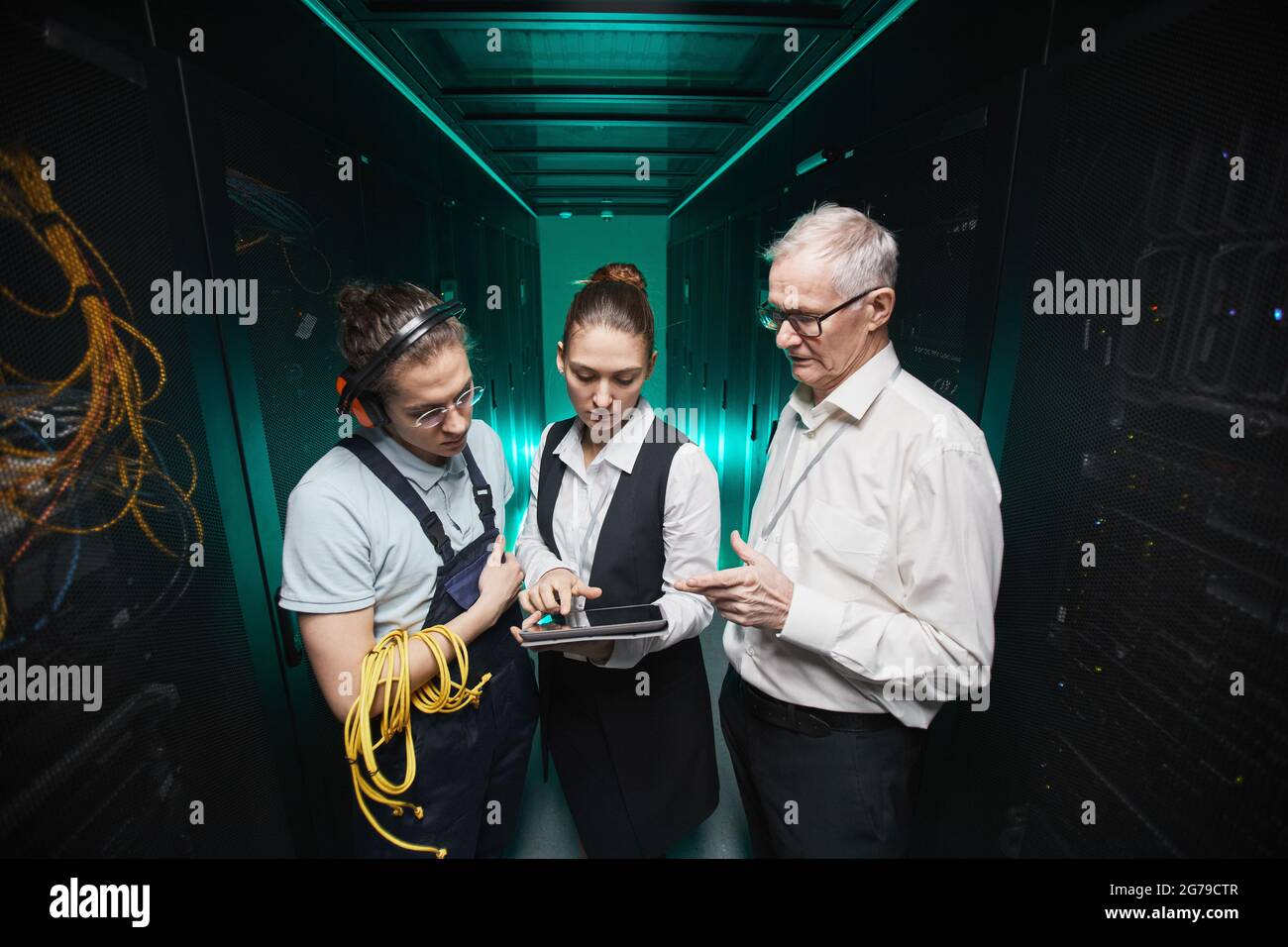 Hochformat von Personen, die ein Tablet im Serverraum verwenden, während Wartungsarbeiten im Rechenzentrum ausgeführt werden, Kopierplatz Stockfoto