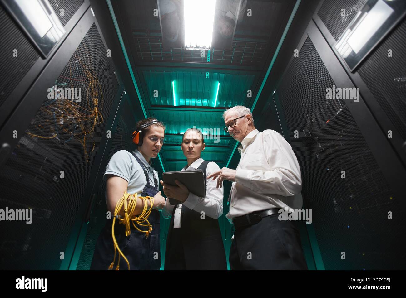 Porträt von Personen, die ein Tablet im Serverraum verwenden, während Wartungsarbeiten im Rechenzentrum ausgeführt werden, Kopierplatz Stockfoto