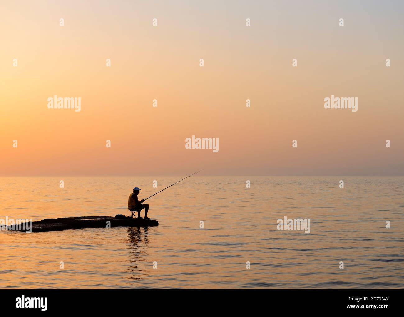 Der Fischer hat sich gegen einen Dämmerung-Himmel geschildet Stockfoto