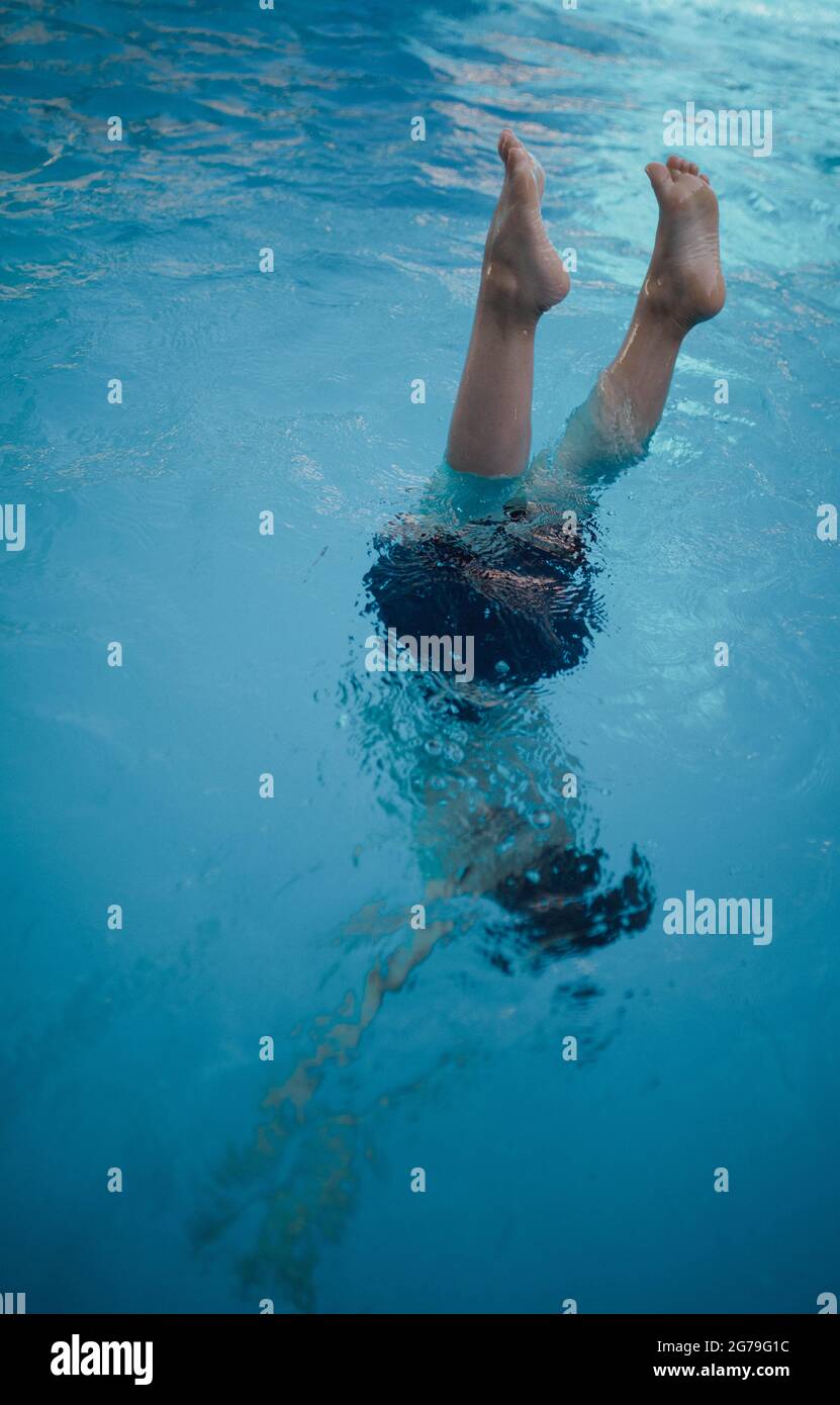 Ein Kind taucht ins Wasser, Füße schauen aus dem Wasser. Stockfoto