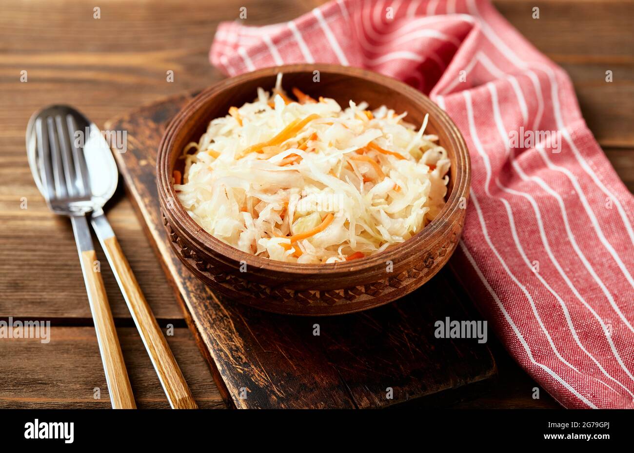 Sauerkraut, fermentierter Kohl mit Karotten in Schüssel auf Holzgrund. Superfoods zur Unterstützung des Immunsystems. Stockfoto