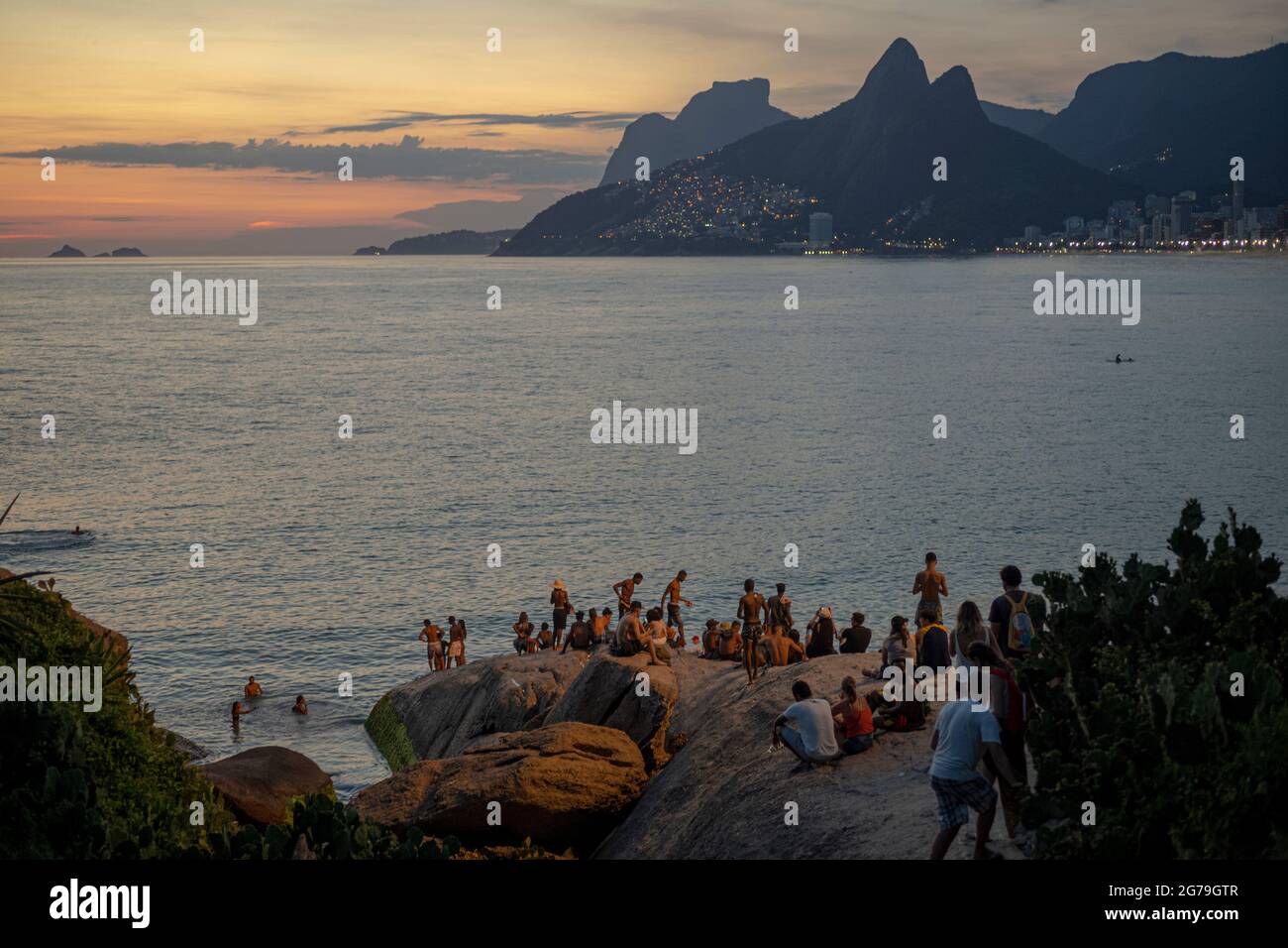 Ein magischer Ort: Die Menschen applaudieren, wenn die Sonne am Arpoador-Felsen untergeht, mit Blick auf den Strand von Ipanema und die Berge von Morro Dois Irmaos und Leblon im Hintergrund. Kamera: Leica M10 Stockfoto