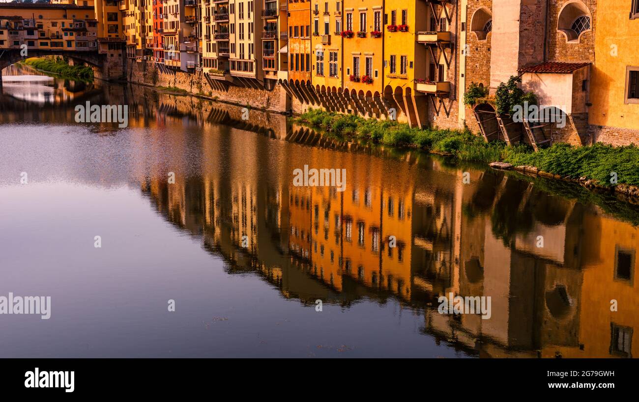 Ponte Vecchio und Arno, Florenz, Toskana, Italien. Warme Töne, lebhaftes, farbenfrohes Gebäude, das sich im klaren Fluss widerspiegelt. Stockfoto
