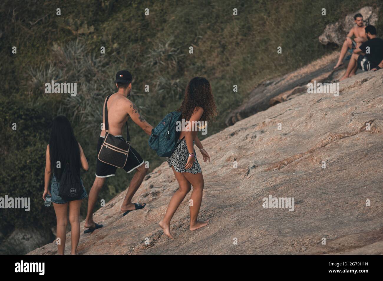 Ein magischer Ort: Die Menschen applaudieren, wenn die Sonne am Arpoador-Felsen untergeht, mit Blick auf den Strand von Ipanema und die Berge von Morro Dois Irmaos und Leblon im Hintergrund. Kamera: Leica M10 Stockfoto