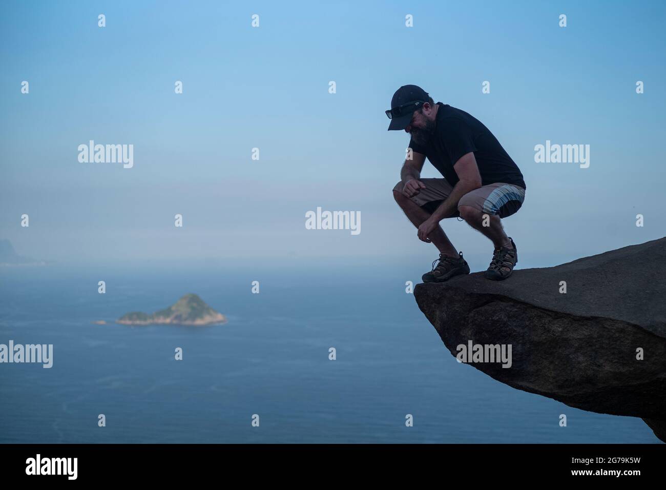 Ein Mann, der den Blick auf die wilden Strände von einem Felsen auf dem Gipfel des Berges Pedra do Telegrafo, Barra de Guaratiba, Rio de Janeiro, Brasilien, genießt. Aufgenommen mit Leica M10 Stockfoto
