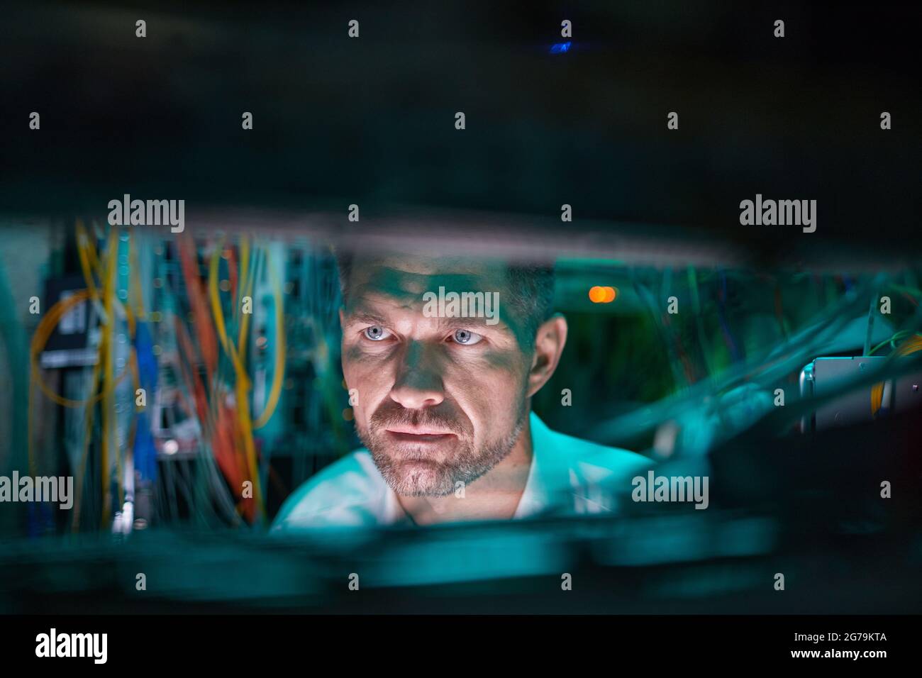 Nahaufnahme eines reifen Netzwerktechnikers, der Server inspiziert, während er mit Supercomputern im Rechenzentrum arbeitet, Speicherplatz kopieren Stockfoto