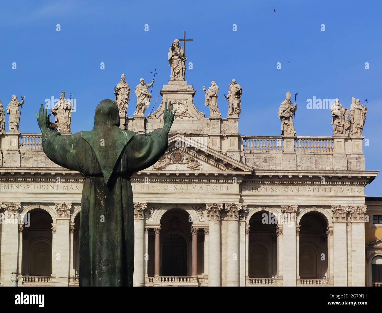 Statue des Heiligen Franziskus mit offenen Armen, die auf die Fassade der Kathedrale von Rom, San Giovanni in Laterano, blicken Stockfoto