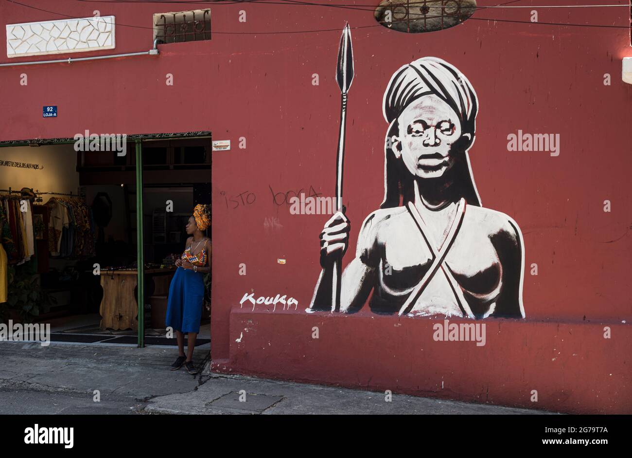 Eine ähnlich aussehende Frau neben einem Graffiti in der Nähe eines Ladens in Santa Teresa, Rio de Janeiro Stockfoto