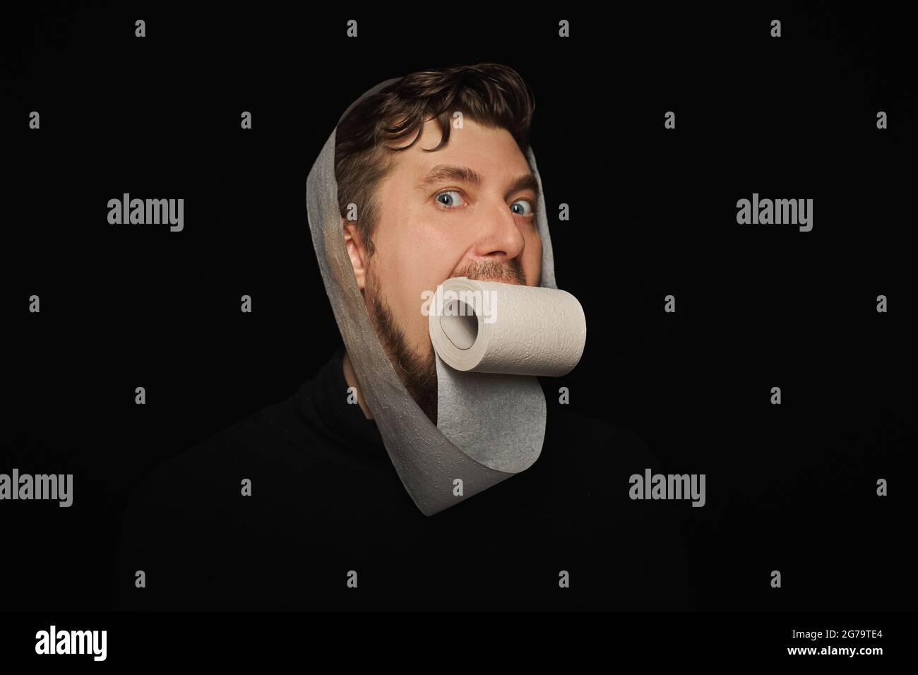 Mann, der Toilettenpapier isst. Lustige Hunger Mann, Fasten Konzept. Hungerstreik. Verrückter bärtiger Kerl. Schwarzer Hintergrund. Stockfoto