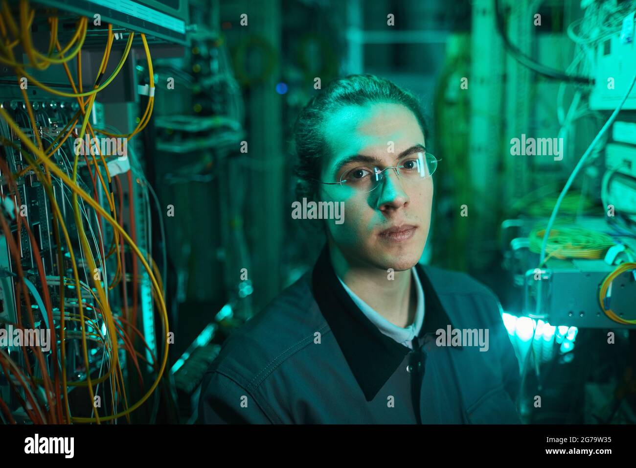 Porträt eines jungen Netzwerktechnikers, der die Kamera im Serverraum betrachtet, während er im Rechenzentrum einen Supercomputer aufstellt und Platz kopiert Stockfoto