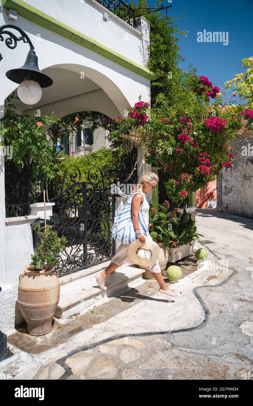 Eine Touristenfrau mit Hut tritt während der Sommerferien aus dem Resort im idyllischen traditionellen Dorf Fiskardo, Kefalonia, Griechenland Stockfoto