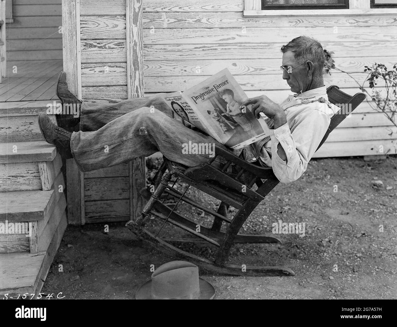 Bauer im Schaukelstuhl beim Lesen des Progressive Farmer. „Farmer Leading his Farm paper“ von George W. Ackerman, Coryell County, Texas, September 1931. Stockfoto