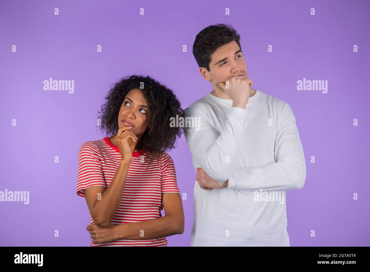 Interracial denken erwägen Paar auf lila Studio-Hintergrund. Mann und Frau schauen in verschiedene Richtungen und jeder denkt über sein Problem nach Stockfoto