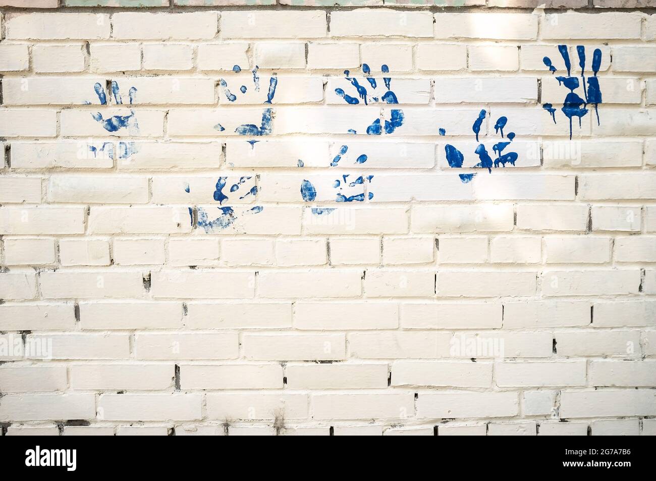 Weiße Ziegelwand mit blauen Handdrucken. Speicherplatz kopieren. Tolle Idee. Abstrakter Hintergrund. Stockfoto