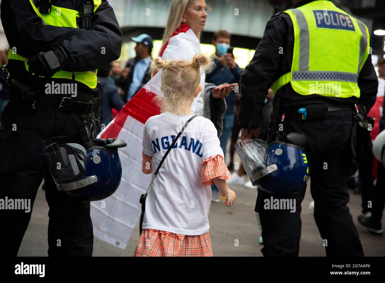 Ein junges Mädchen passiert Polizeilinien, während sich England-Fans auf dem Leicester Square vor dem EM 2020-Finale England gegen Italien versammeln. Stockfoto