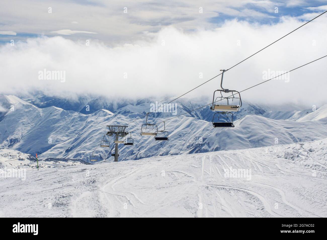 Ein leerer Sessellift auf dem Hintergrund schneebedeckter Grate wurde festgezogen. Das Konzept der aktiven Winterrekreation Stockfoto