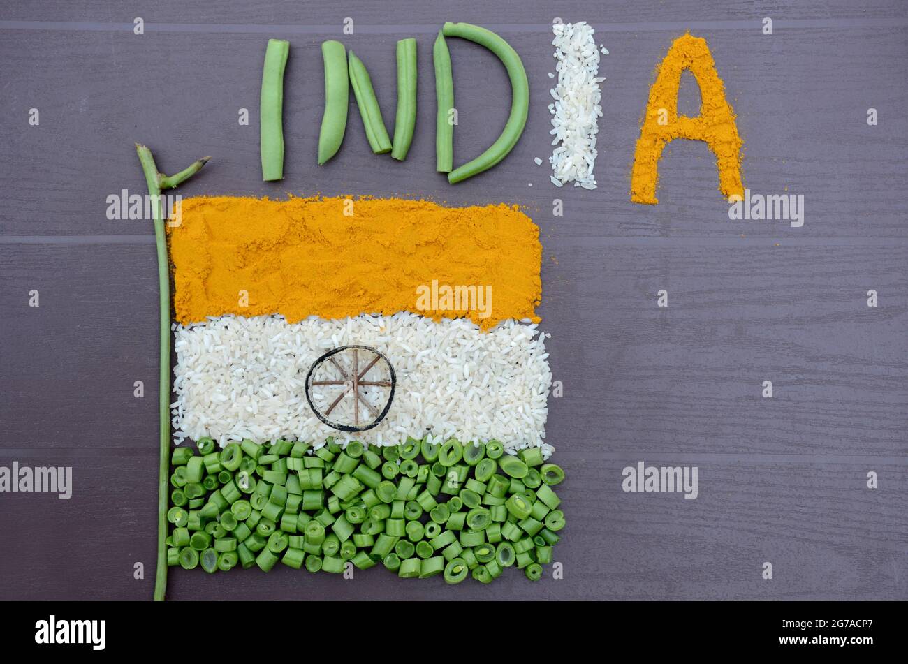 Nahaufnahme orangefarbener Kurkuma, weißer Reis, grünes Bohnen-Gemüse mit dem Gedenktag der indischen Flagge oder des Veteranentages auf dem braunen Hintergrund. Stockfoto