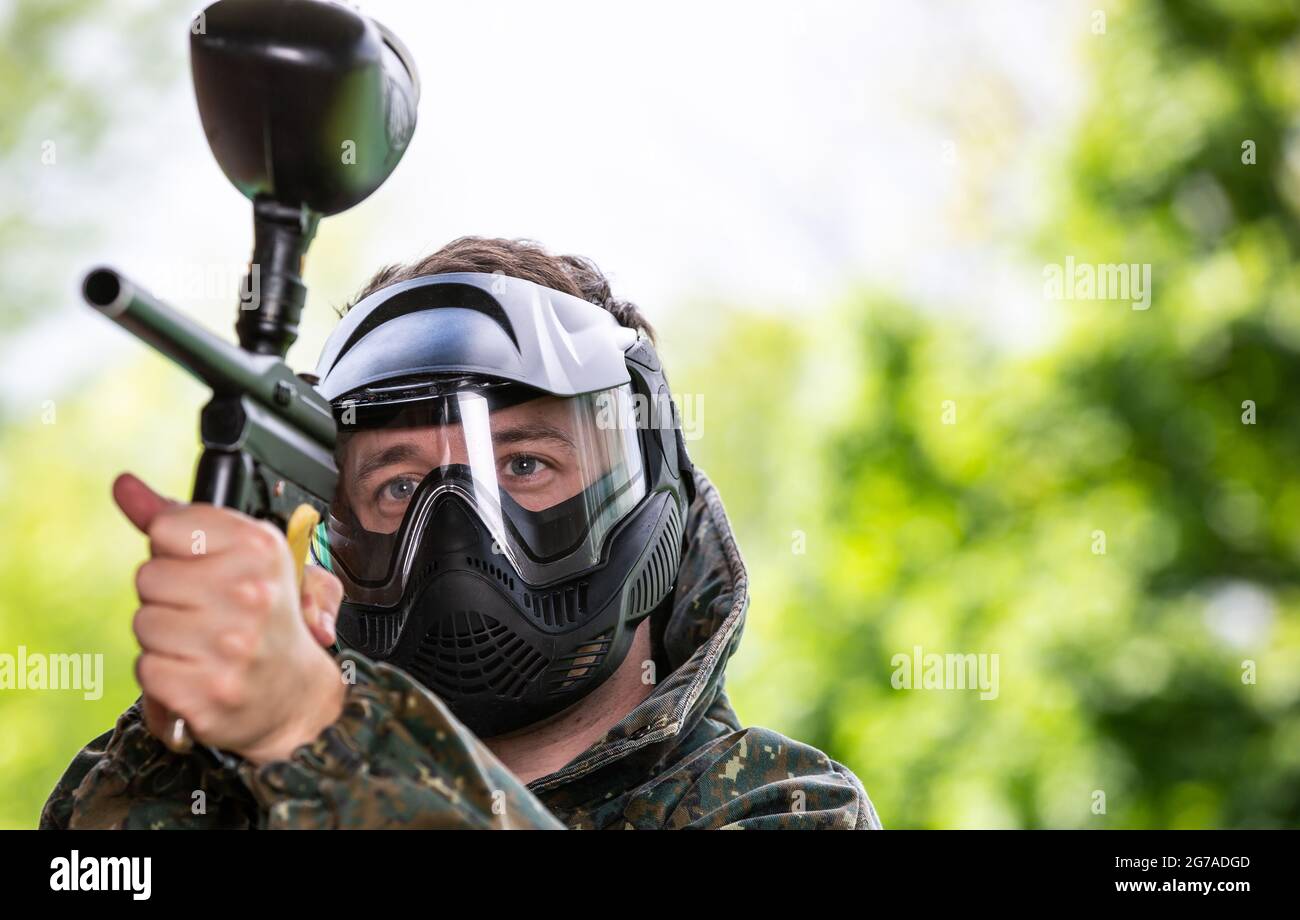 Portrait des jungen Mannes mit Gesichtsmaske und Pistole in der Action-Spiel Paintball, simulieren militärischen Kampf mit Luftgewehren, um Kapseln von Farbe auf schießen Stockfoto