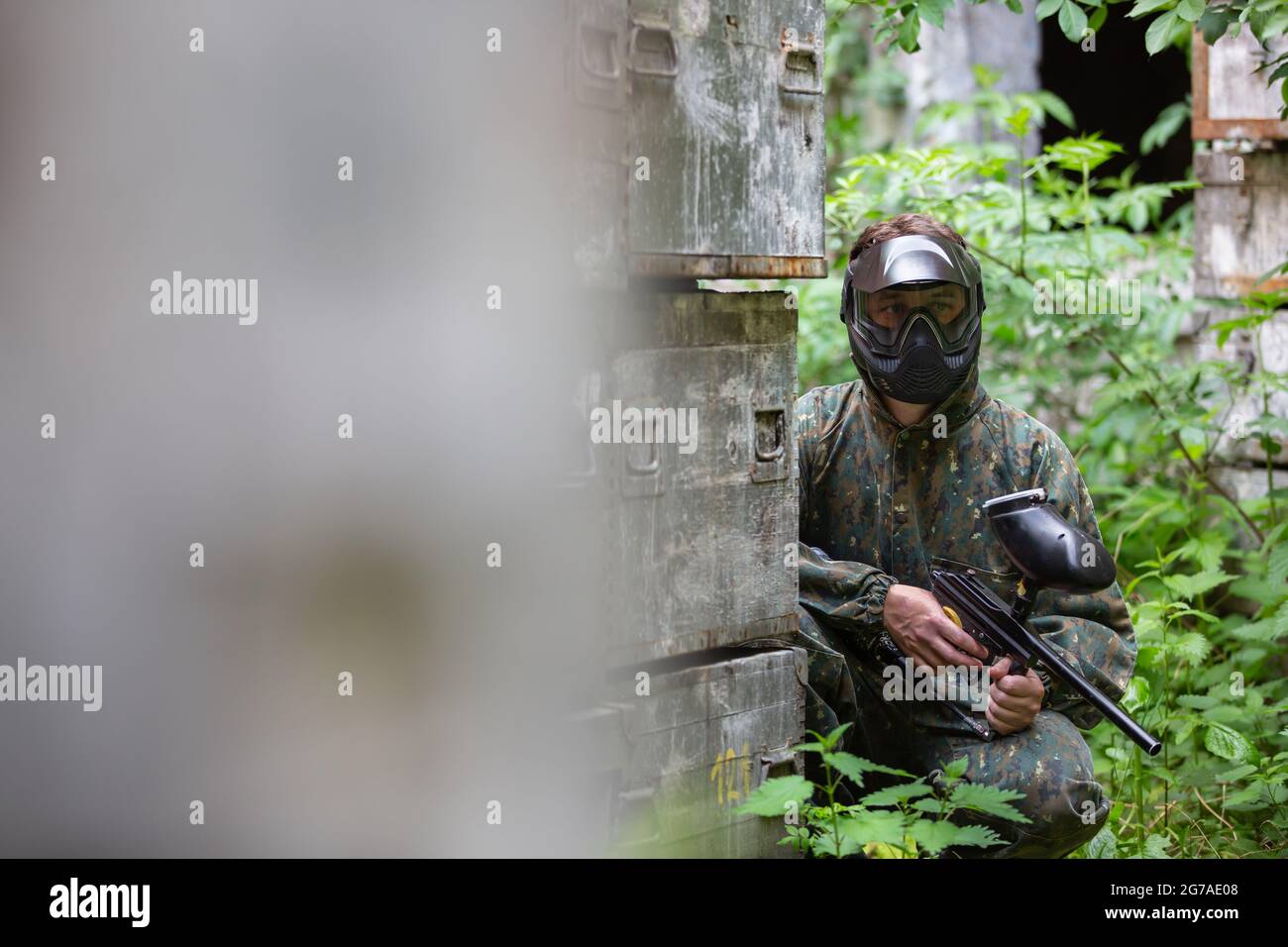 Portrait des jungen Mannes mit Gesichtsmaske und Pistole in der Action-Spiel Paintball, simulieren militärischen Kampf mit Luftgewehren, um Kapseln von Farbe auf schießen Stockfoto