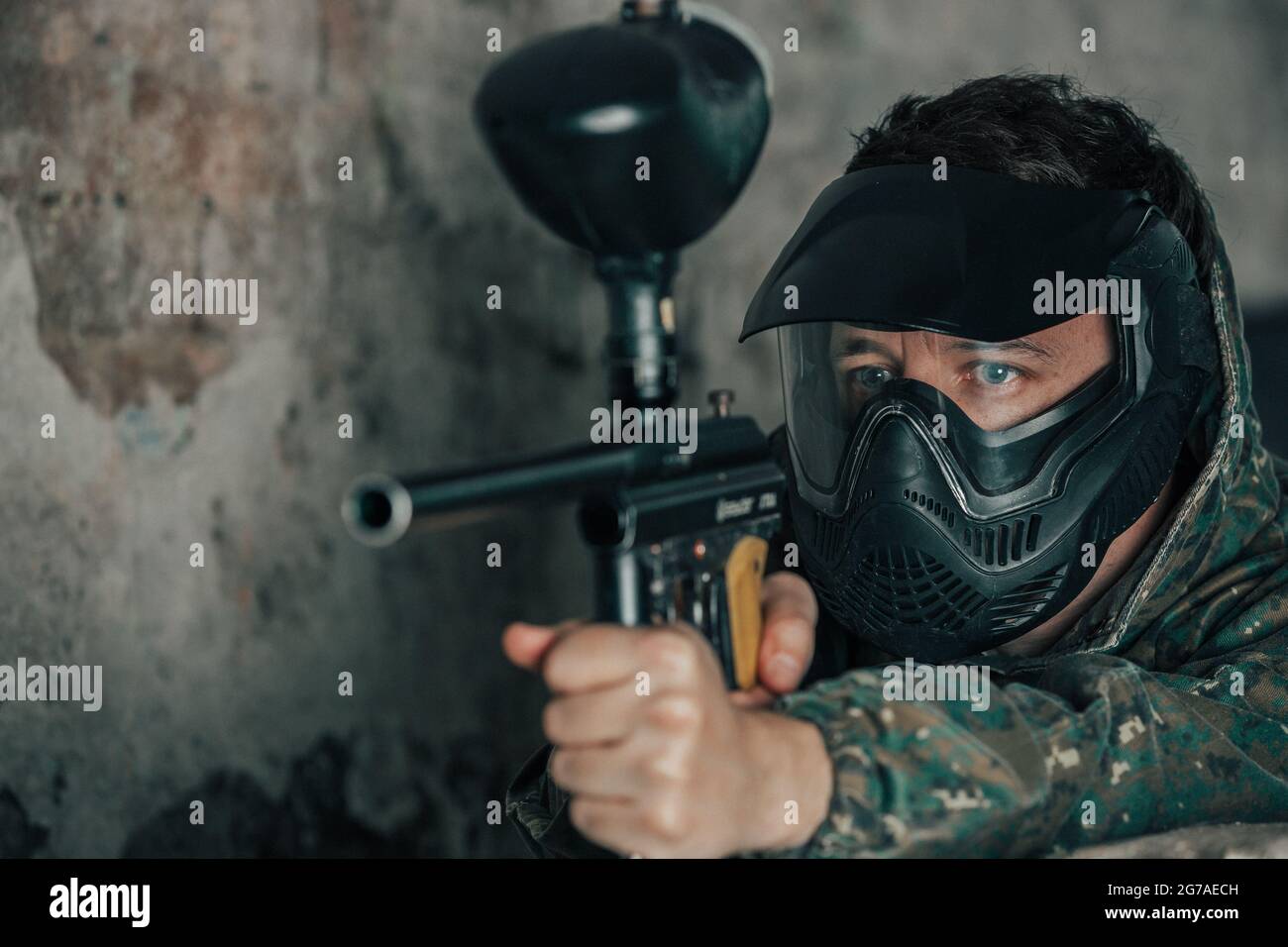 Portrait des jungen Mannes mit Gesichtsmaske und Pistole in der Action-Spiel Paintball, simulieren militärischen Kampf mit Luftgewehren, um Kapseln von Farbe auf schießen Stockfoto