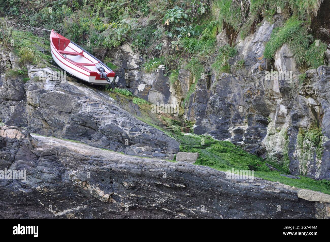 Kleines Boot auf einem steilen, mit Moos bedeckten Slipway in Bessy's Cove, Prussia Cove in der Nähe von Penzance in Cornwall, England, Großbritannien Stockfoto