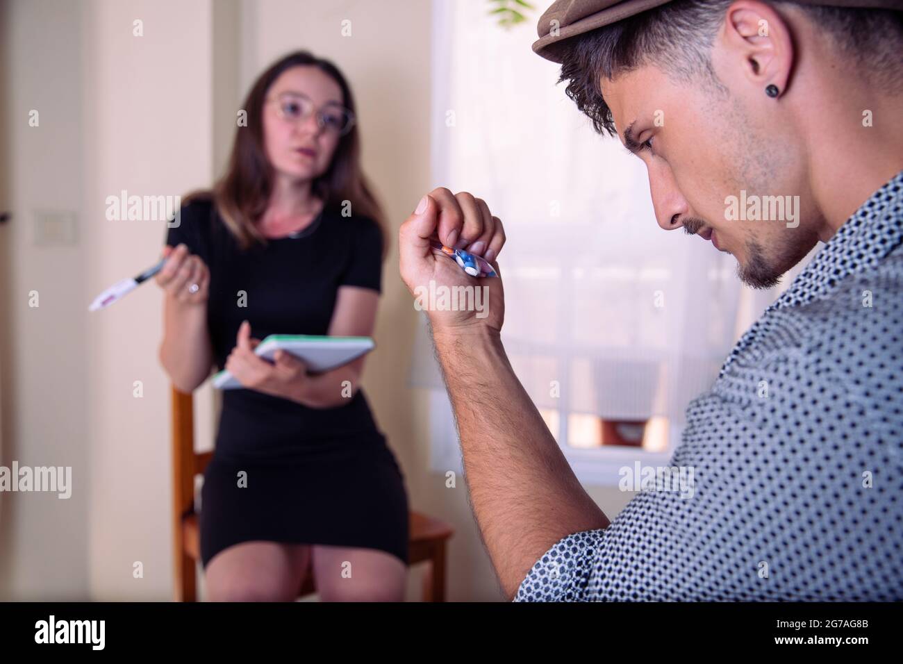 Ein Mann bei einem Besuch beim Psychologen, er hat die ihm verordneten psychiatrischen Medikamente in der Hand, er denkt und schaut sie an, die Psychologen Stockfoto