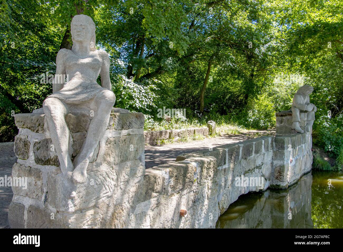 Der Roman - Märchenwesen Jungfrau und Wassermann, sitzt auf einer Steinbrücke über einem Strom fließt aus einem Teich, Tschechien. Stockfoto