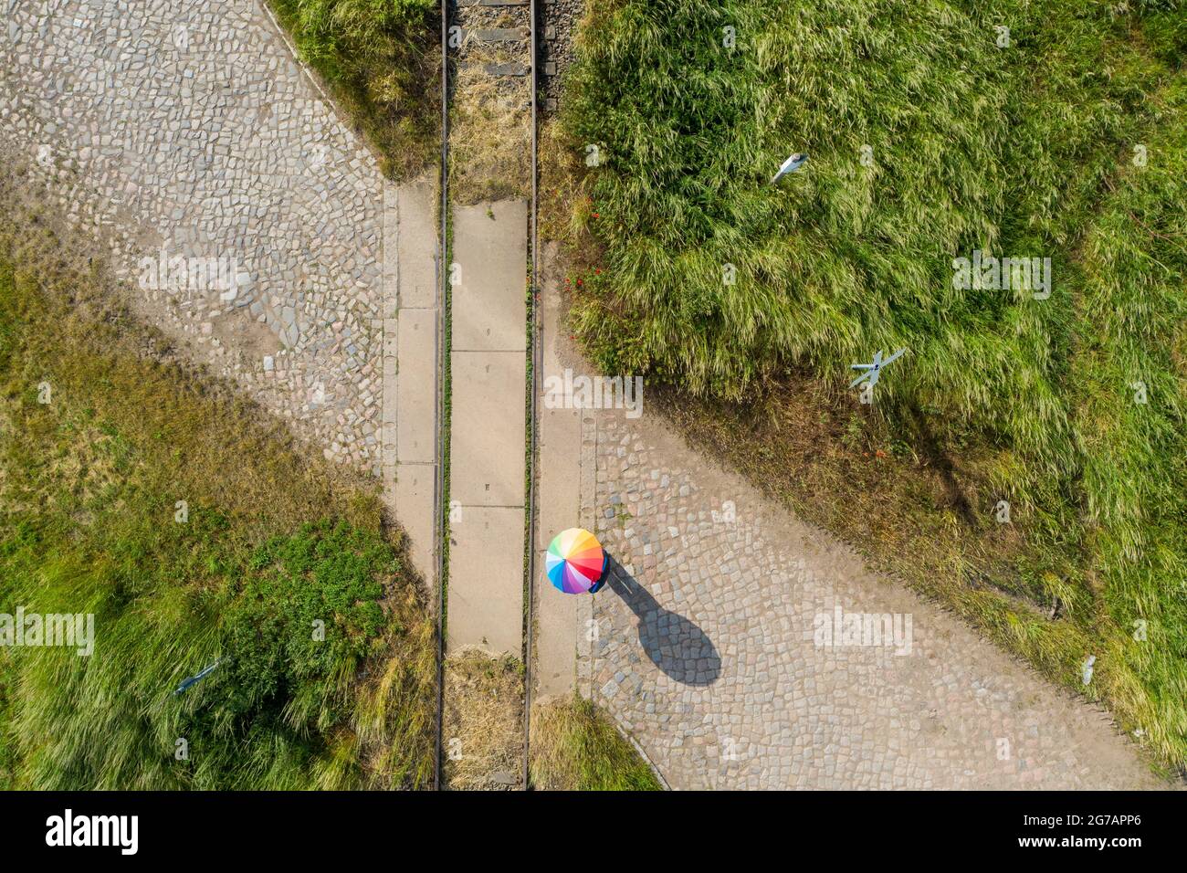 Eine Person steht mit einem Regenschirm auf einer stillgebrachten Eisenbahnstrecke Stockfoto