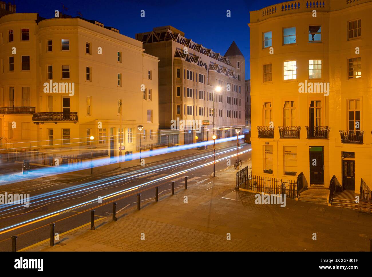 Kreuzung des unteren Teils des Brunswick Place am oberen Ende des Brunswick Square und der Western Road, Hove. Morgendämmerung. Regency-Gehäuse, beleuchtet von Straßenlaternen. Leichte trais vom vorbeifahrenden Straßenfahrzeug. Brighton & Hove, East Sussex, England, Großbritannien Stockfoto