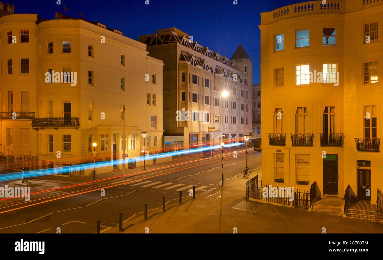 Kreuzung des unteren Teils des Brunswick Place am oberen Ende des Brunswick Square und der Western Road, Hove. Morgendämmerung. Regency-Gehäuse, beleuchtet von Straßenlaternen. Leichte trais vom vorbeifahrenden Straßenfahrzeug. Brighton & Hove, East Sussex, England, Großbritannien Stockfoto