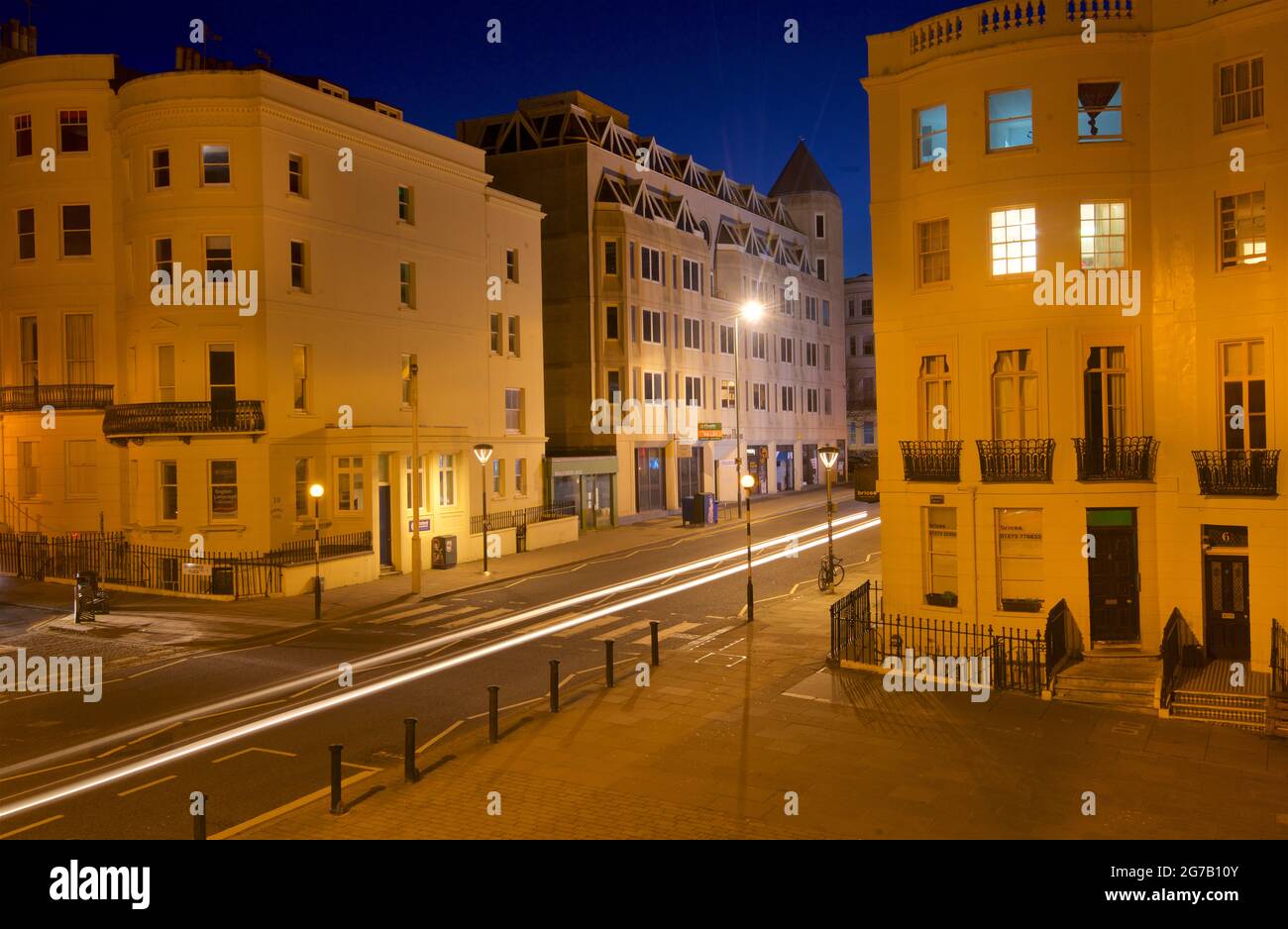 Kreuzung des unteren Teils des Brunswick Place am oberen Ende des Brunswick Square und der Western Road, Hove. Morgendämmerung. Regency-Gehäuse, beleuchtet von Straßenlaternen. Leichte trais vom vorbeifahrenden Straßenfahrzeug. Brighton & Hove, East Sussex, England, Großbritannien Stockfoto