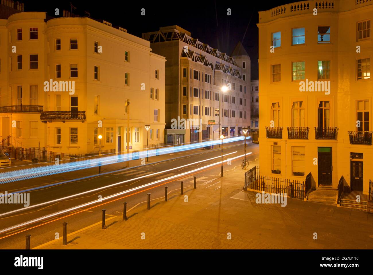 Kreuzung des unteren Teils des Brunswick Place am oberen Ende des Brunswick Square und der Western Road, Hove. Morgendämmerung. Regency-Gehäuse, beleuchtet von Straßenlaternen. Leichte trais vom vorbeifahrenden Straßenfahrzeug. Brighton & Hove, East Sussex, England, Großbritannien Stockfoto