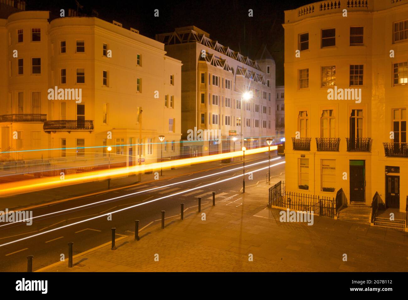 Kreuzung des unteren Teils des Brunswick Place am oberen Ende des Brunswick Square und der Western Road, Hove. Morgendämmerung. Regency-Gehäuse, beleuchtet von Straßenlaternen. Leichte trais vom vorbeifahrenden Straßenfahrzeug. Brighton & Hove, East Sussex, England, Großbritannien Stockfoto