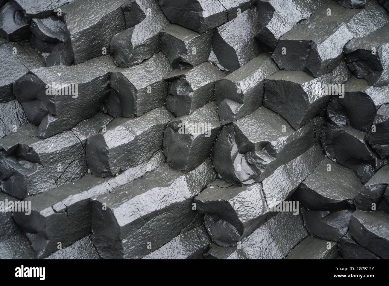 Nahaufnahme von Basaltsäulen am schwarzen Sandstrand. Island Stockfoto