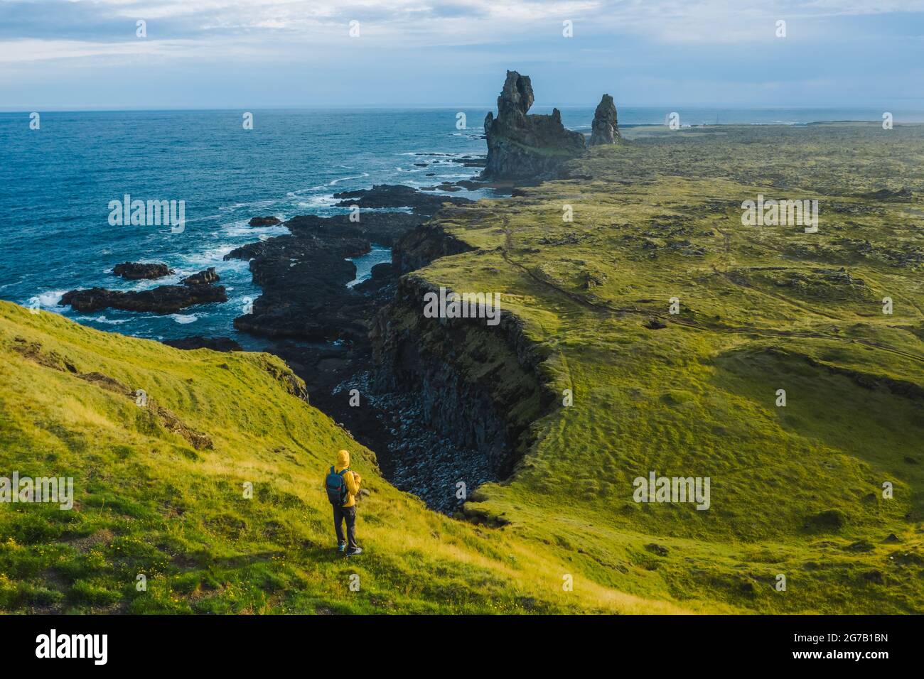 Mann Wanderer in gelber Jacke stehen auf dem Gipfel des Felsens im Outdoor-Park in Island. Londrangar Stockfoto