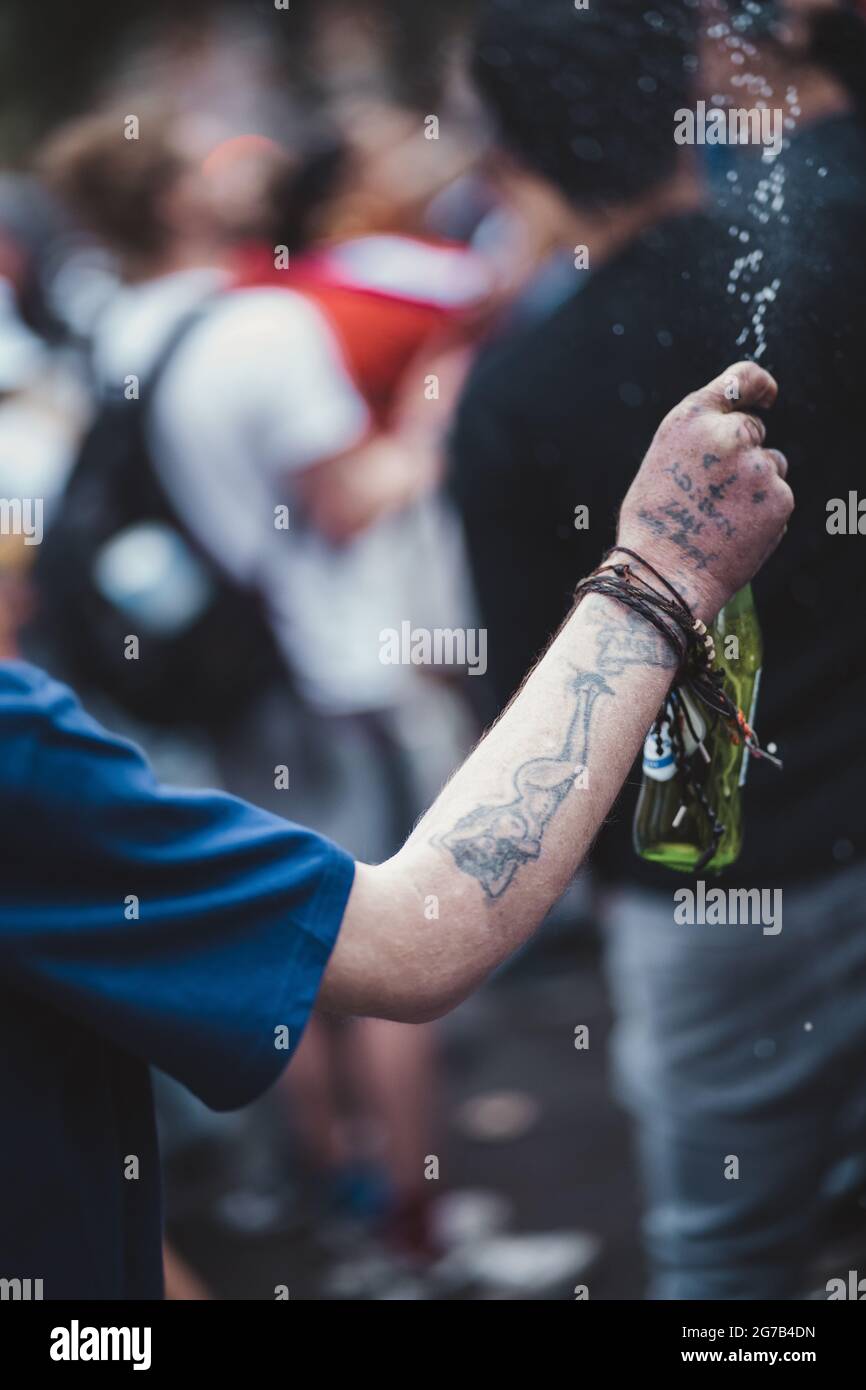 London | UK - 2021.07.12: Mann spritzt Menschen mit einem Bier auf dem Leicaster Square Stockfoto