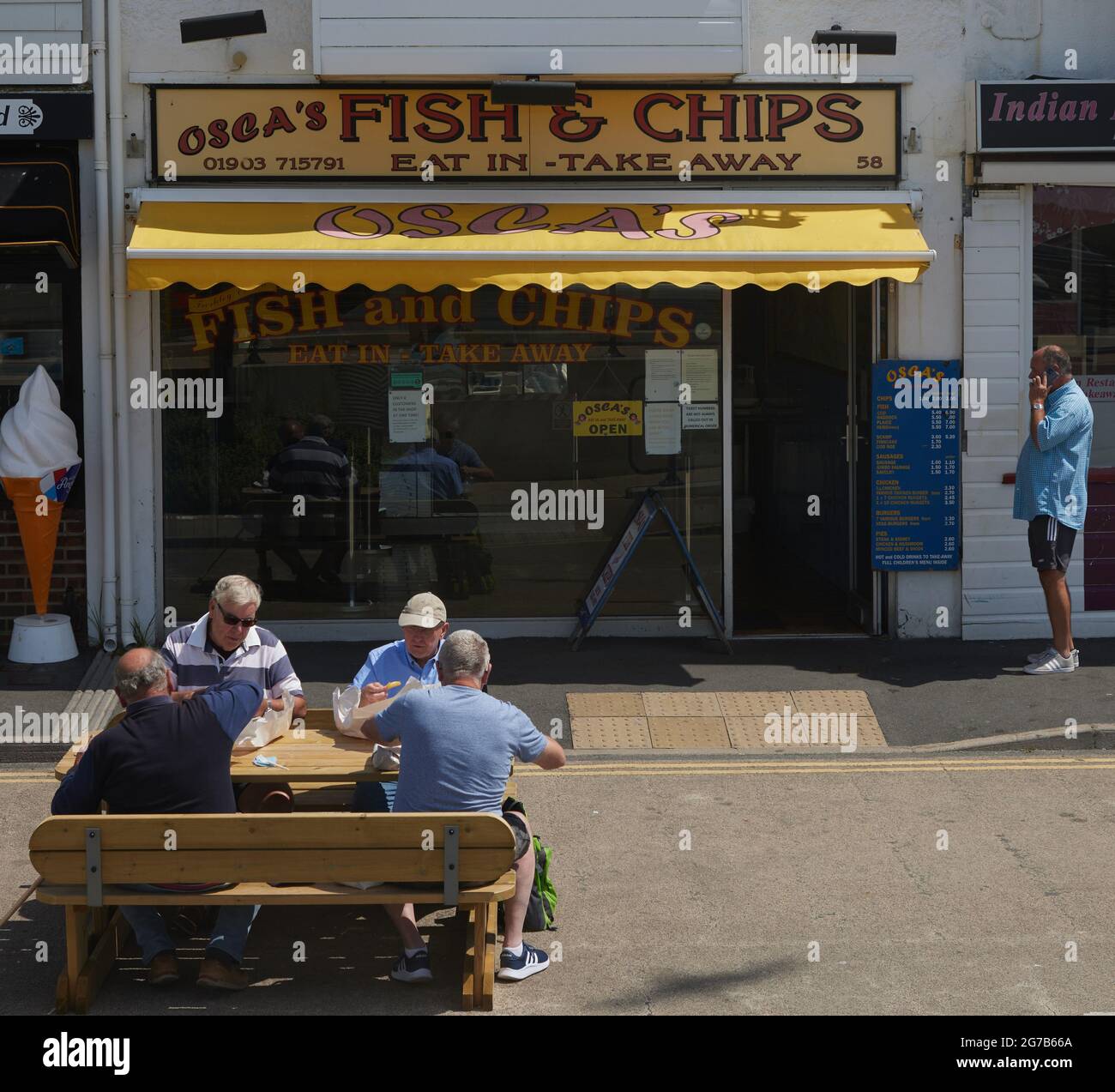 Menschen, die gerne Fisch und Schiffe auf der Straße von Littlehampton, Großbritannien, essen. Stockfoto