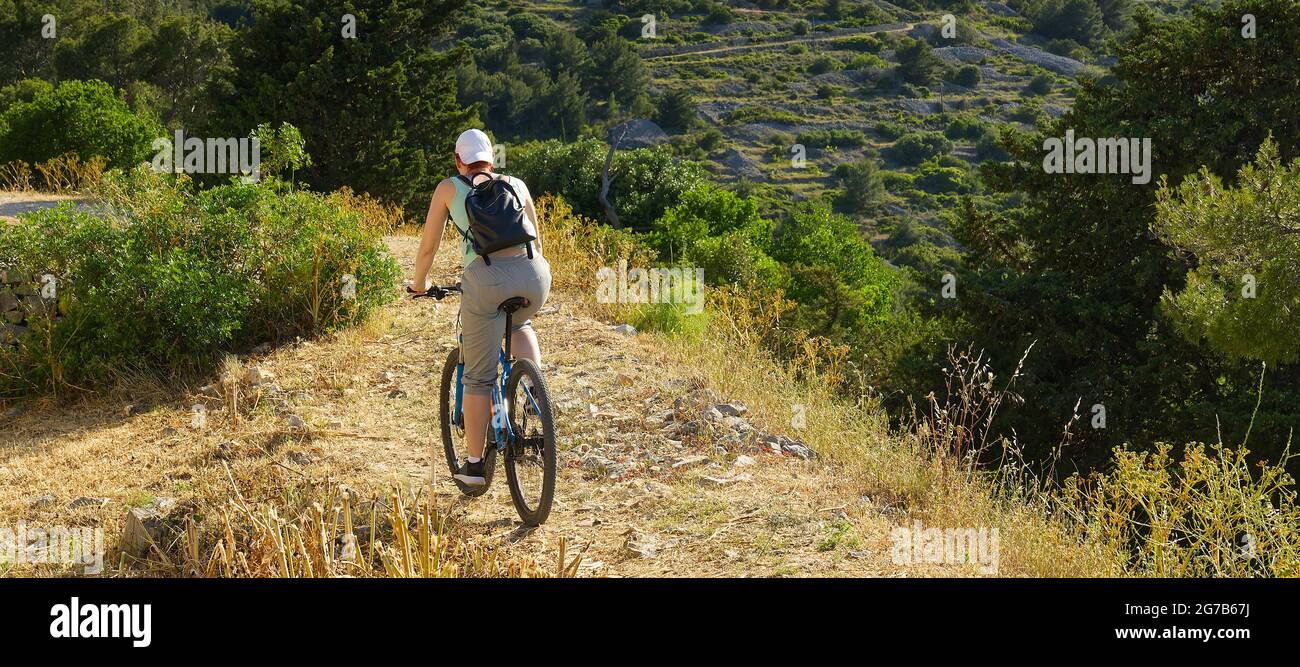 Eine Radfahrerin fährt an einem sonnigen Sommertag auf einem Bergweg mit ihrem Mountainbike. Stockfoto